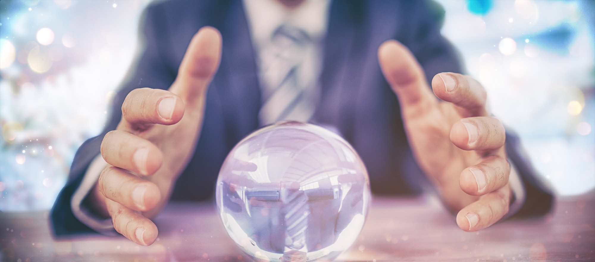 Man's hand held close to a crystal ball, trying to see into the recruitment future, sparkles in the background suggesting that Christmas may be a good moment to reevaluate your recruitment agency and think about what might be happening in the future so you can plan for it.