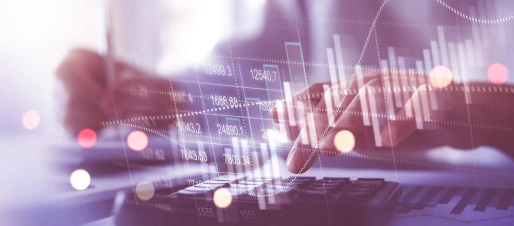 A person using a calculator and writing with overlaid financial charts and data.
