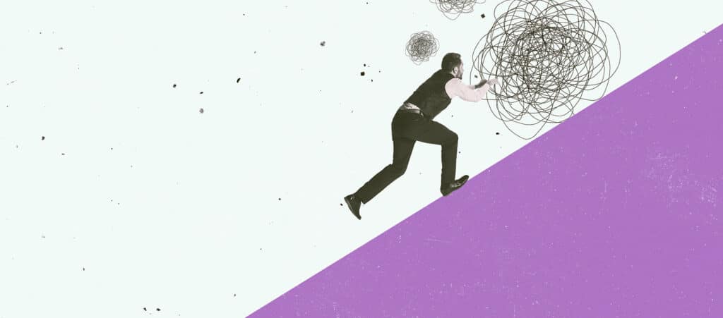 Business man trying to run up a purple hill with a messy ball in front of him a concept that suggest that starting a new business particularly a recruitment agency is hard going.