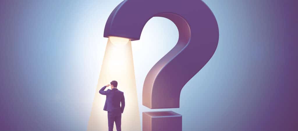 A businessman standing inside the light of a giant question mark, representing the uncertainty recruitment agencies face when choosing a pay-and-bill provider without expert accountancy services.