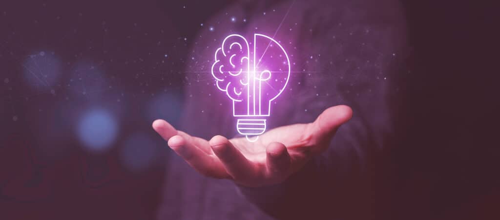 A glowing brain and light bulb graphic over a hand, representing strategic financial planning and cash flow strategies for recruitment agencies.