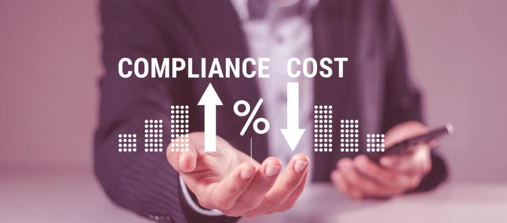 A business professional holding a glowing digital overlay showing 'COMPLIANCE COST' text with percentage signs, bar charts, and directional arrows.